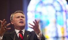 Dr. Mark Harris, preaching in front of a stain glass window.