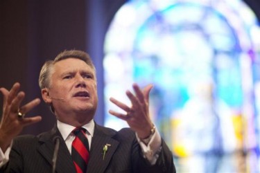 Dr. Mark Harris, preaching in front of a stain glass window.