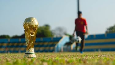 World Cup Trophy on soccer field with player in the background