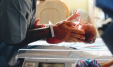 Newborn baby being placed on a scale by a nurse