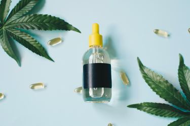 marijuana leaves with pills and bottle on blue background