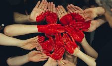 Hands forming a red heart on a black background