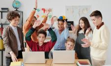 Children at school sitting around two laptops celebrating an opportunity