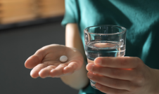 Woman holding white pill and a glass of water