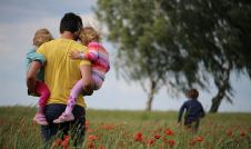 Father walking through field with three children