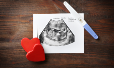 Ultrasound picture on a table with a pregnancy test and hearts